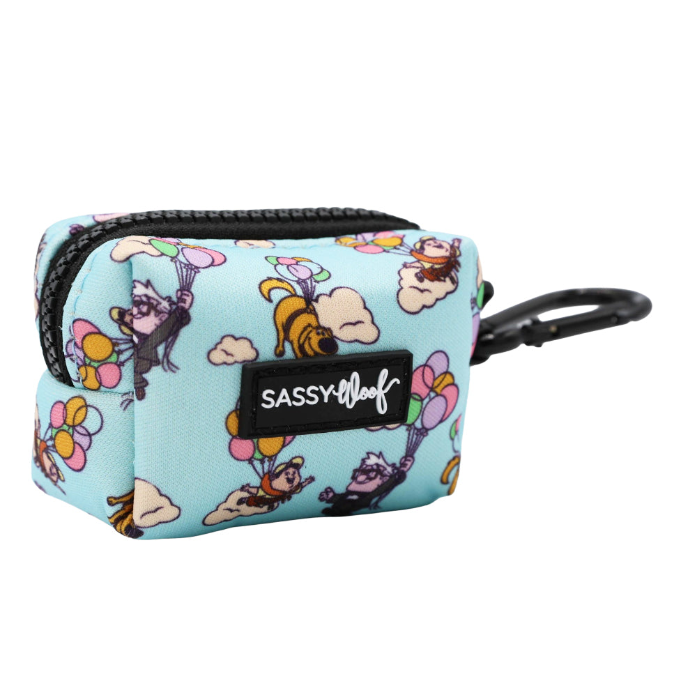 The Sassy Woof Dog Waste Bag Holder - Disney and Pixar's Up is a small, rectangular, light blue pouch with a black zipper, carabiner, dog and balloon print, and a black SASSY WOOF logo patch on the front.