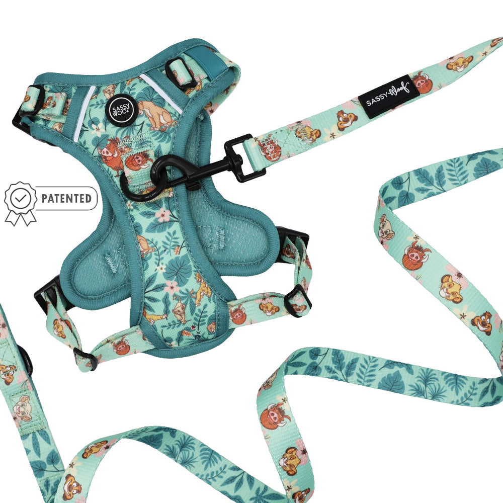 Sassy Woof’s Dog Two Piece Bundle – Disney’s The Lion King Wild Kingdom, a teal harness and leash set featuring cartoon animal and foliage prints, is laid flat on a white background. This jungle-themed dog harness showcases a small patented badge near the harness.