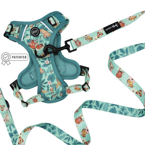 Sassy Woof’s Dog Two Piece Bundle – Disney’s The Lion King Wild Kingdom, a teal harness and leash set featuring cartoon animal and foliage prints, is laid flat on a white background. This jungle-themed dog harness showcases a small patented badge near the harness.