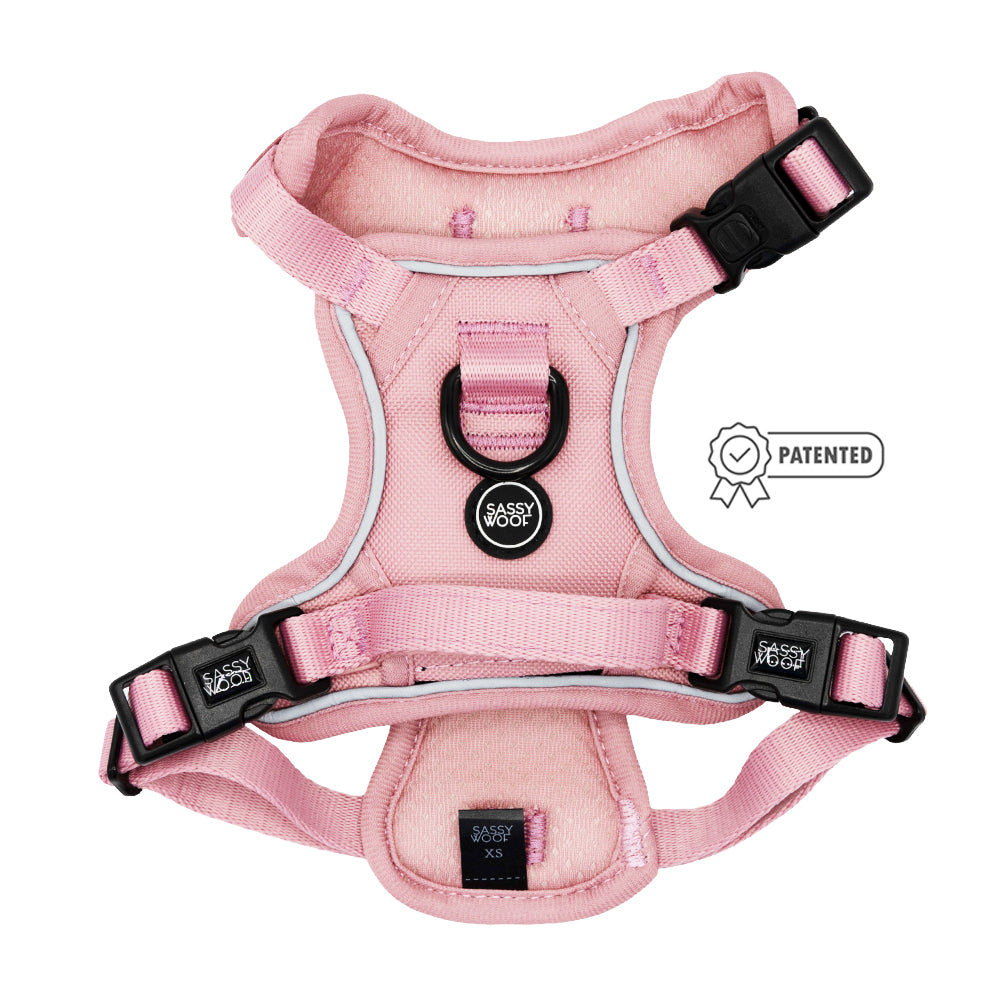 The Sassy Woof Dog Step-in Harness in Dusty Rose features black buckles, reflective straps, and a center label, shown on a white background with a small Patented badge to the right.