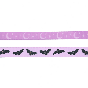 Two strips of purple ribbon evoke the enchanting look of the Sassy Woof Dog Leash - Lil Batty: the top showcases crescent moons and stars, reminiscent of a dreamy autumn night, while the bottom displays black bats with white eyes and tiny orange noses set against a purple background—capturing that perfect bat-themed vibe from Sassy Woof’s signature design.