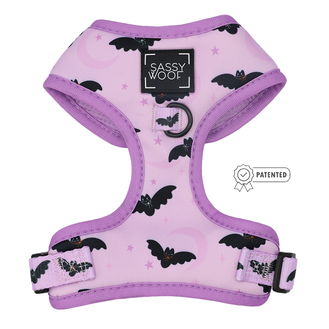 Introducing the Dog Adjustable Harness - Lil Batty by Sassy Woof: this lavender harness features a whimsical bat pattern, adjustable straps, a secure ring for leash attachment, and the classic black Sassy Woof logo. A patented icon is displayed to the right—ideal for adding some spooky charm to your dog’s walk this Fall.
