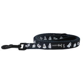 The Dog Leash - Lil Boo Thing by Sassy Woof is a rolled-up black dog leash adorned with white ghost illustrations and finished with a black clasp. As part of the Lil Boo Thing Dog Collection, this Halloween leash also displays an official Sassy Woof label.