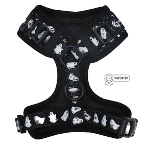 The Sassy Woof Dog Adjustable Harness - Lil Boo Thing is a black harness adorned with white cartoon ghosts, some holding lanterns, and printed stars. This Halloween dog harness features adjustable straps, sturdy metal rings, durable plastic buckles, and a Patented badge icon on the right side.