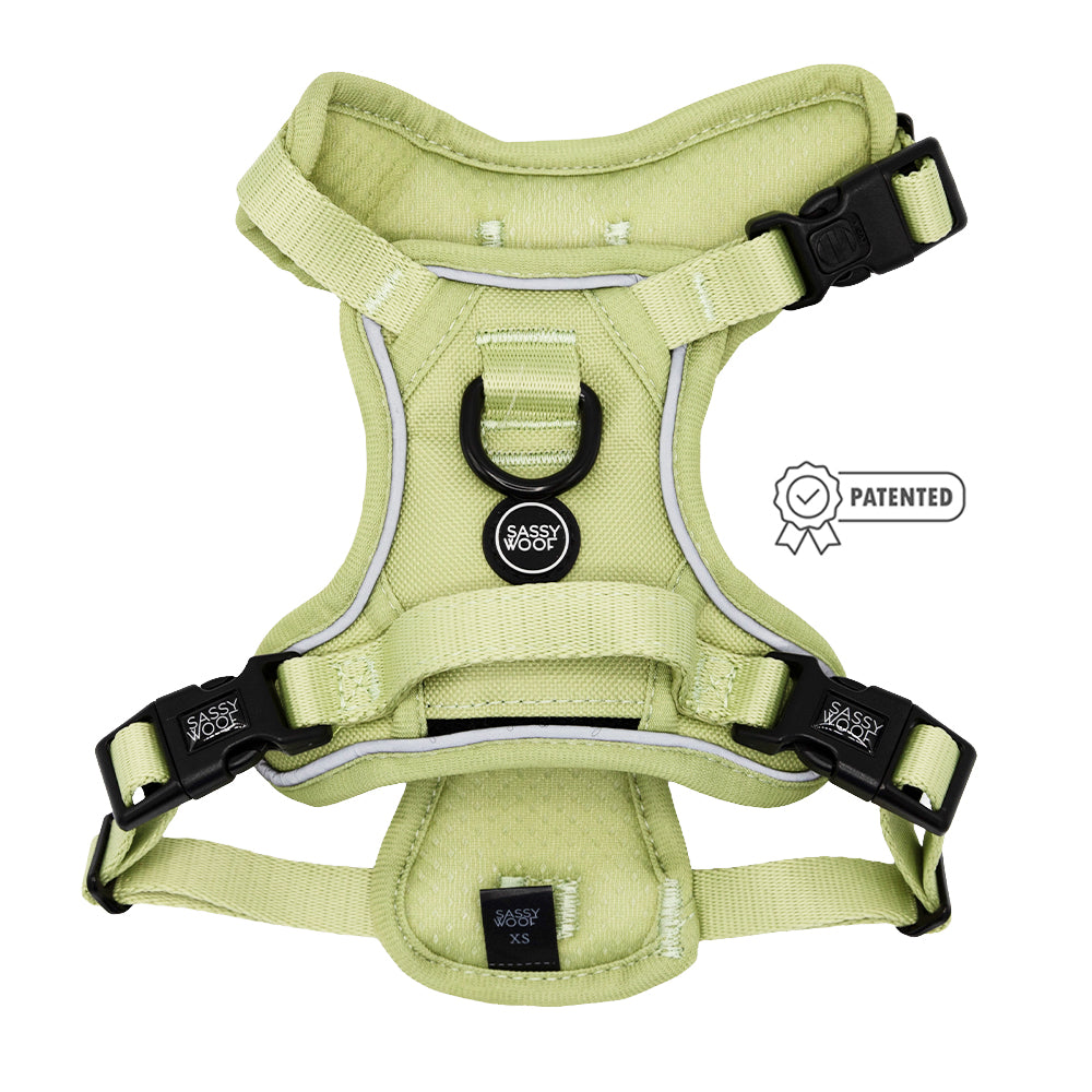 The Sassy Woof Dog Step-in Harness - Matcha is light green with adjustable reflective straps, black buckles, a black metal D-ring, Air Tag pocket, Sassy Woof logo on the front, and a Patented badge icon beside it.