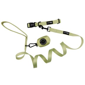 A light green retractable dog leash with black clasp, adjustable strap, handle loop, and Sassy Woof brand tag features a small round case labeled SAFETY WOOD. Pairs perfectly with the Matcha dog collar in the Dog Three Piece Bundle - Matcha.