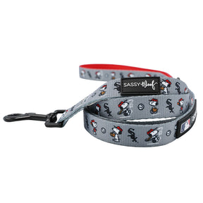 The Sassy Woof Dog Leash - MLB™ x Peanuts™ Chicago White Sox™ features a gray design with Snoopy in a baseball cap, black hardware, Sassy Woof label, small MLB logo, and red inner lining—ideal for sporty pups.