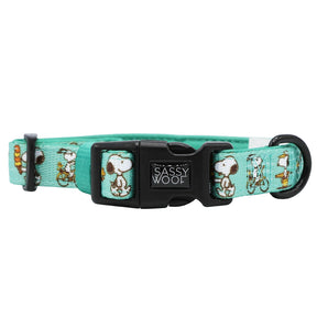 The Sassy Woof Dog Collar - Peanuts™ Road Trippin’ is a teal adjustable collar with Snoopy designs, a black plastic buckle, and a metal D-ring—stylish and comfortable gear for your adventure dog.
