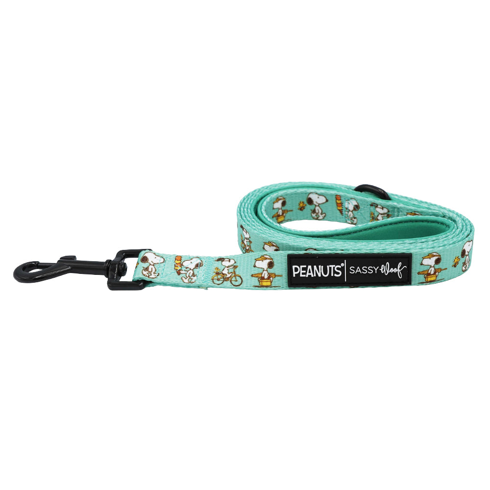 The Dog Leash - Peanuts™ Road Trippin' by Sassy Woof features a teal color with playful Snoopy designs, a black clasp, and a PEANUTS Sassy Woof label—combining comfort and style for every adventure-loving pup.