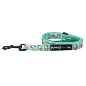 The Dog Leash - Peanuts™ Road Trippin' by Sassy Woof features a teal color with playful Snoopy designs, a black clasp, and a PEANUTS Sassy Woof label—combining comfort and style for every adventure-loving pup.