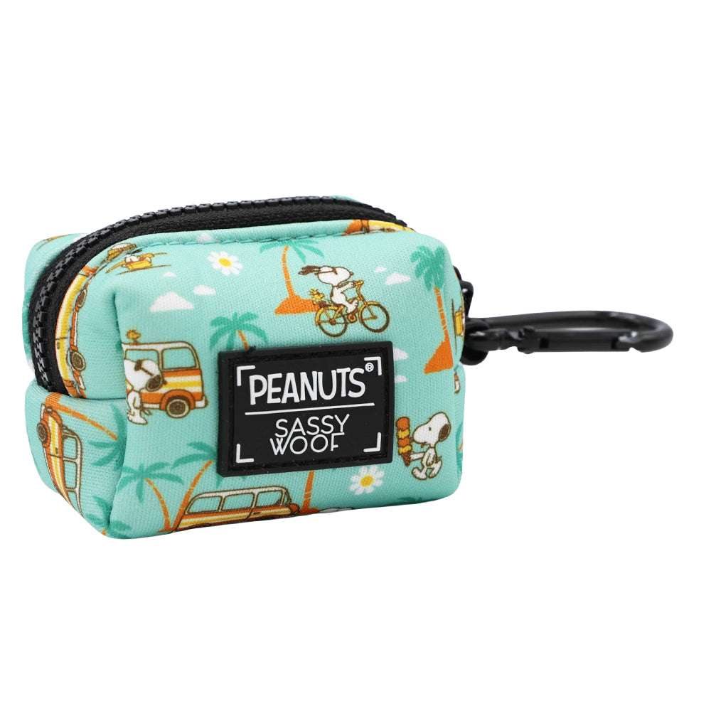 The Sassy Woof Dog Waste Bag Holder - Peanuts™ Road Trippin’ is a small teal neoprene pouch with Snoopy, palm trees, and buses. Features a black zipper, clip, and “Peanuts Sassy Woof” label. Matches your favorite dog harness—perfect for adventures!.