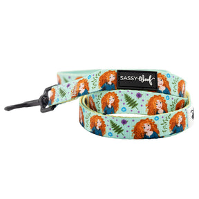 The Sassy Woof Harness Three Piece Bundle – Disney's Merida features a dog leash with a light blue background, cartoon Merida in a blue dress, green leaves, purple flowers, and a black Sassy Woof label.