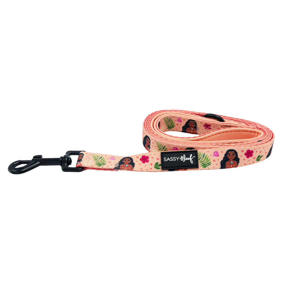 The Sassy Woof Dog Leash - Disney’s Moana is a rolled-up pink padded leash with a black clip, cute dog and floral illustrations, a black SASSY WOOF label, and pairs perfectly with any ocean-inspired harness.