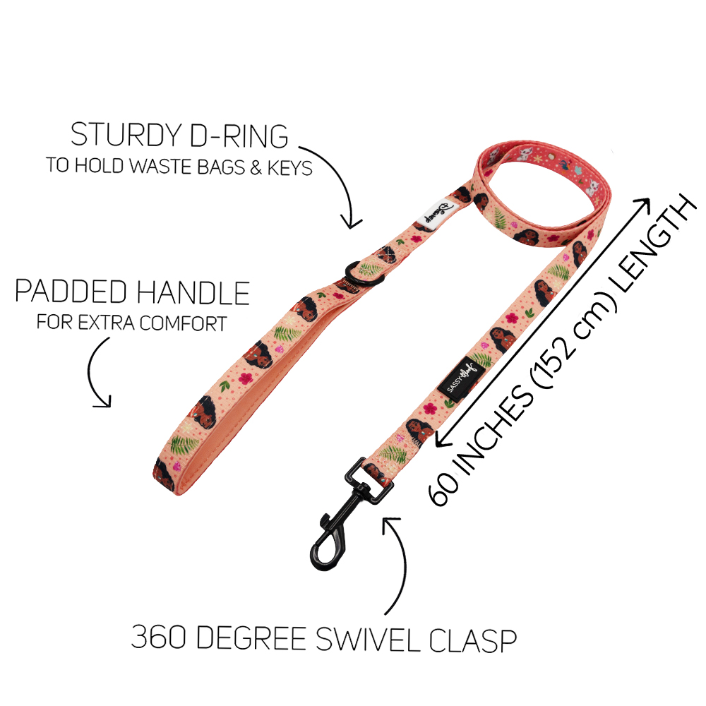 The Sassy Woof Dog Leash - Disney's Moana features a floral, padded design, sturdy D-ring for waste bags/keys, 360° swivel clasp, and a 60-inch length. Ocean details match your favorite Moana harness. Features labeled in black text with arrows.
