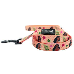 The Sassy Woof Dog Two Piece Bundle – Disney’s Moana features a peach-colored leash with a lively design of cartoon women, flowers, and green leaves, plus a black metal clasp and logo patch—perfect to pair with your Disney Moana dog harness.