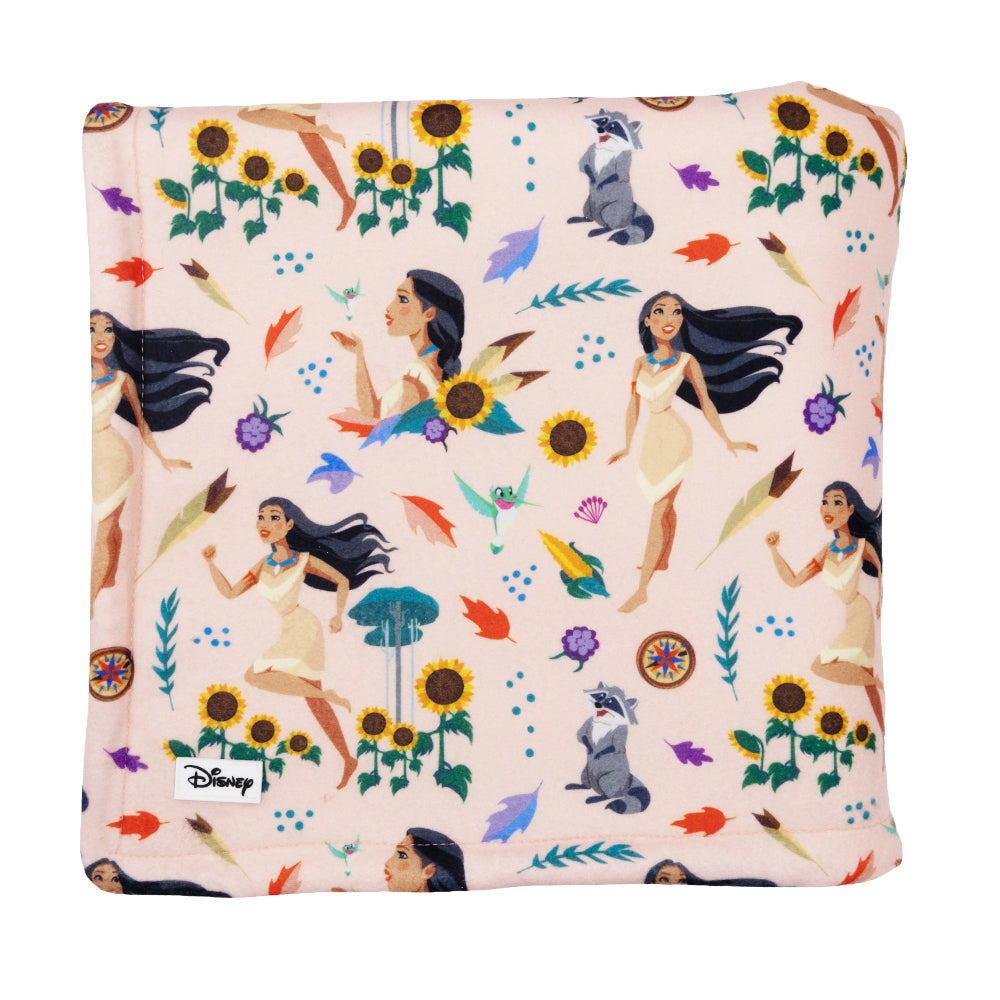 The Sassy Woof Pet Blanket - Disney's Pocahontas features a square shape with illustrations of Pocahontas, leaves, sunflowers, raccoons, and birds in a repeating pattern on a light pink background.