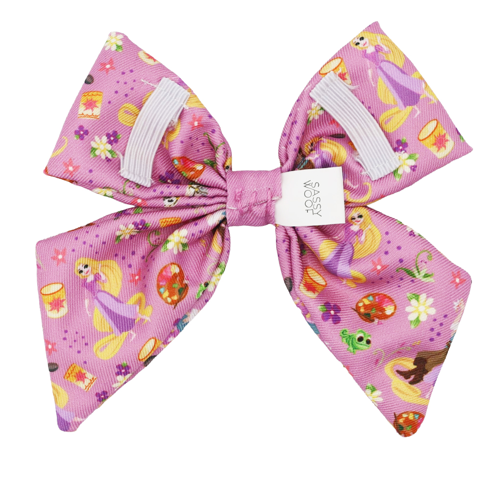 The Sassy Woof Dog Sailor Bow - Disney's Rapunzel features a large pink bow with Rapunzel, lanterns, flowers, and Pascal from Tangled—ideal for Disney dog accessory fans and any Tangled-inspired dog collection.