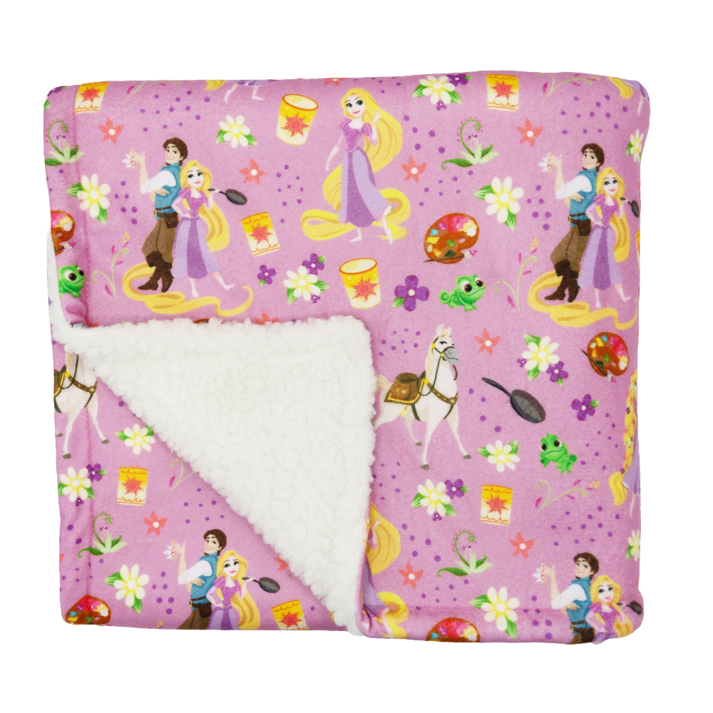 The Sassy Woof Pet Blanket - Disney's Rapunzel features a soft pink design with a white sherpa lining and colorful illustrations of Rapunzel, Flynn Rider, Pascal, and Tangled-themed accents on a purple background.