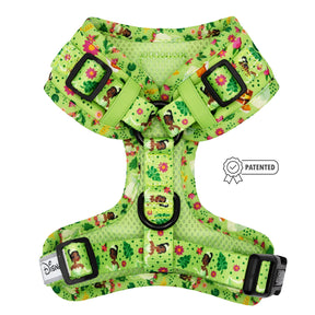 A green Disney dog harness by Sassy Woof featuring Tiana-themed illustrations, tropical flowers, a patented badge graphic, adjustable straps with black buckles, and Disney branding on the strap.