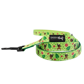 The Sassy Woof Harness Three Piece Bundle - Disney's Tiana features a green design with leaves, pink flowers, cartoon dogs in flower crowns, and is finished with a black Sassy Woof label.