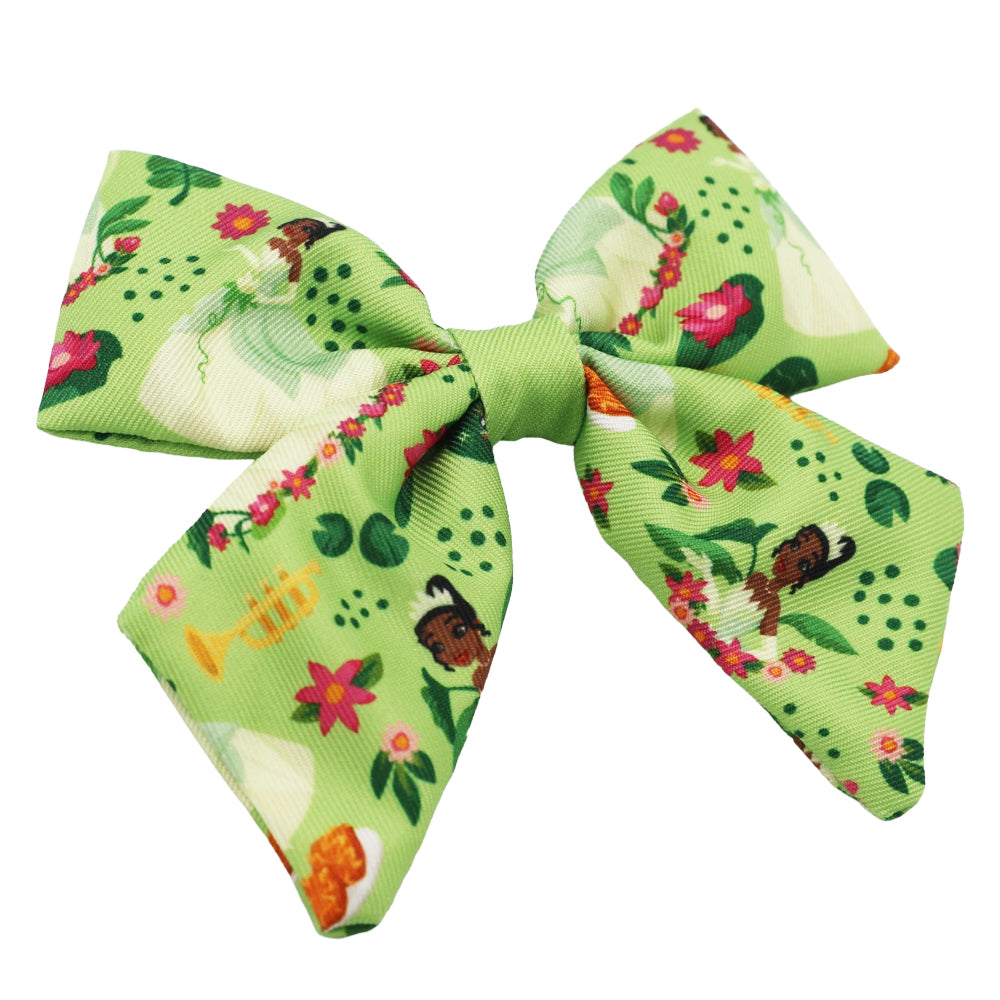 The Sassy Woof Dog Sailor Bow - Disney's Tiana features a large green bow with colorful flowers, playful Tiana illustrations, and musical instruments—perfect for fans of Princess and the Frog or to match the Princess and the Frog dog harness.
