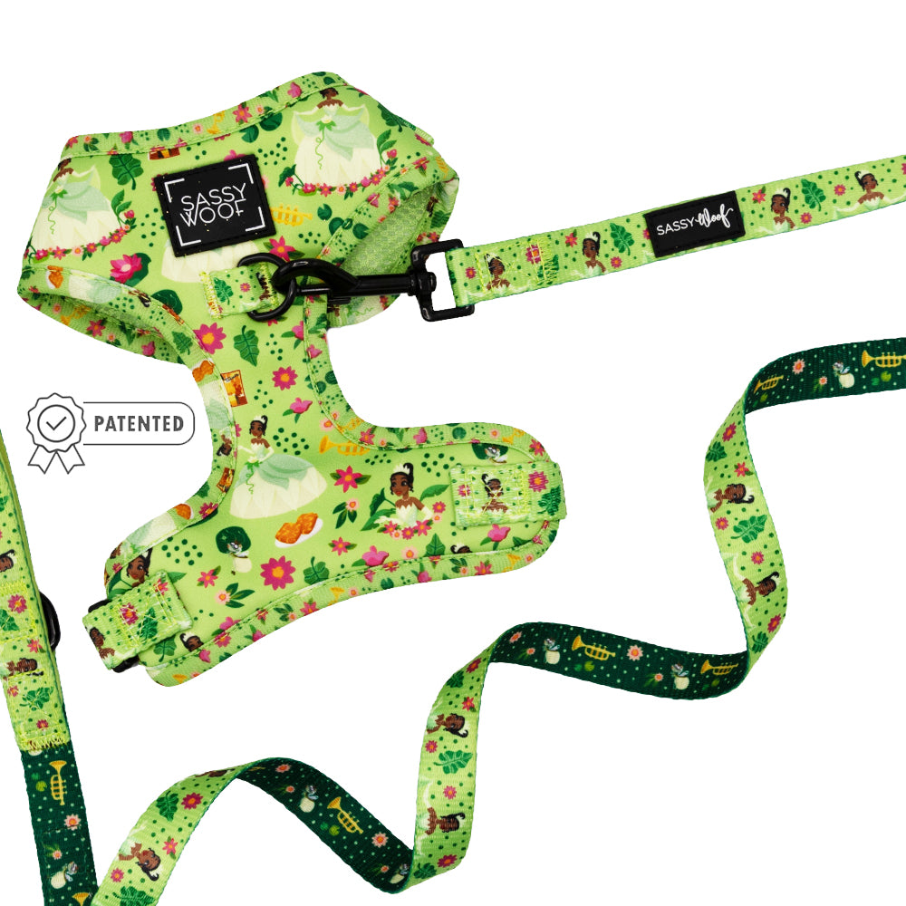 The Sassy Woof Disney’s Tiana Dog Two Piece Bundle features a bright green adjustable harness and leash set with a whimsical fairy tale pattern, “Sassy Woof” label, and patented badge icon.