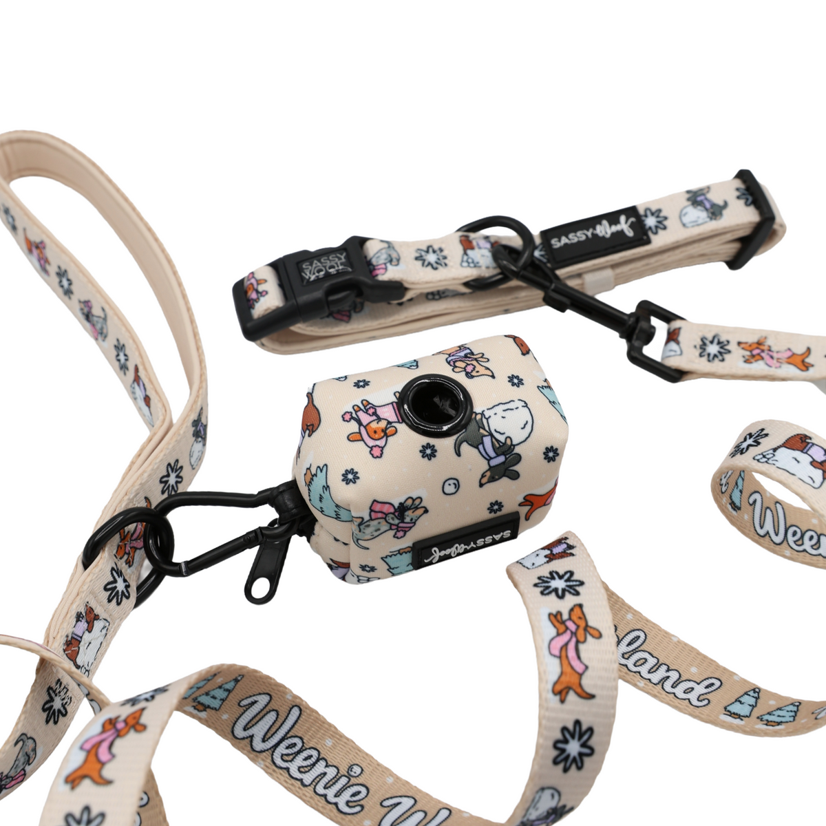 Introducing the Sassy Woof Dog Collar Three Piece Bundle from the Weenie Wonderland Collection—a festive set featuring a beige dog leash and waste bag holder adorned with playful cartoon dogs, bones, and trees. The leash is detailed with “Weenie World,” black hardware, and a secure clip attachment, making it ideal for pairing with your favorite winter dachshund accessories or collar.