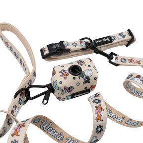 Introducing the Sassy Woof Dog Collar Three Piece Bundle from the Weenie Wonderland Collection—a festive set featuring a beige dog leash and waste bag holder adorned with playful cartoon dogs, bones, and trees. The leash is detailed with “Weenie World,” black hardware, and a secure clip attachment, making it ideal for pairing with your favorite winter dachshund accessories or collar.