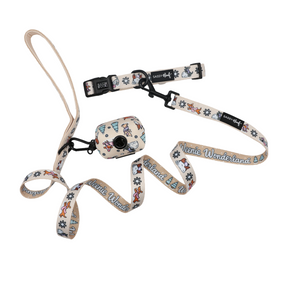 Celebrate the holidays with the Sassy Woof Dog Collar Three Piece Bundle - Weenie Wonderland. This festive set includes a beige leash printed with “Weenie Wonderland,” a matching dog collar, and a coordinating waste bag holder, all featuring dachshunds, snowflakes, and tree patterns from the Weenie Wonderland Collection. The items are displayed on a white background.