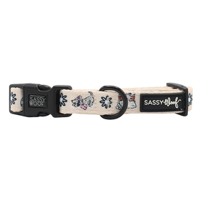 Add playful charm to your festive dog accessories collection with the Sassy Woof Dog Collar - Weenie Wonderland, featuring a cream-colored adjustable design, cartoon French bulldog faces, black hardware, and signature Sassy Woof labels on the clasp and strap.