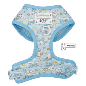 The Dog Adjustable Harness – Cinnamoroll™ by Sassy Woof features light blue fabric with white and blue cartoon characters, stars, and candy. It has a patented badge, Cinnamoroll x Sassy Woof branding, and a no-pull design for comfort.