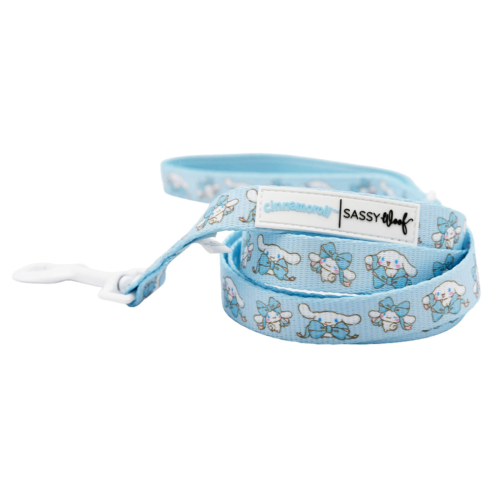 The Sassy Woof Dog Four Piece Bundle - Cinnamoroll™ features a light blue leash with Cinnamoroll and blue bows, a white clasp, and branded tags. Perfect to pair with a matching Cinnamoroll dog harness!.