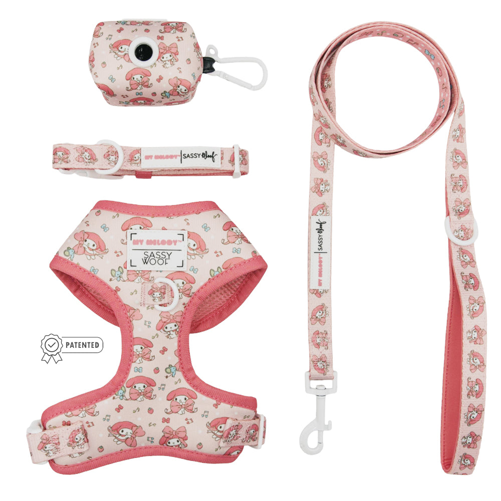 The Sassy Woof Dog Four Piece Bundle - My Melody™ features a pink harness, leash, collar, and waste bag holder with a cartoon mushroom and fox pattern—perfect for fans of My Melody dog accessories. Each piece is displayed flat on a white background.