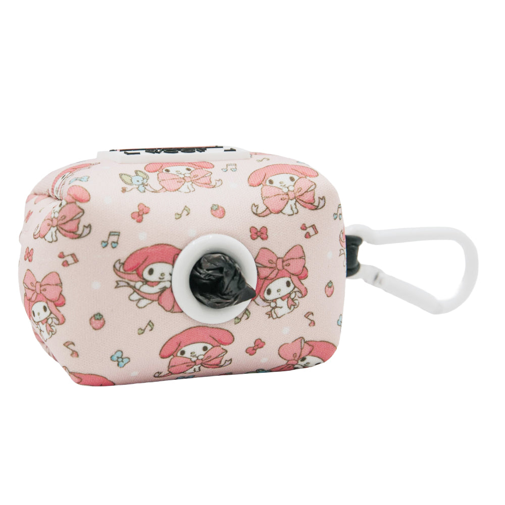 The Sassy Woof Dog Waste Bag Holder - My Melody™ is a pink, rectangular dispenser with a white clip and cute cartoon rabbit designs, bows, strawberries, and musical notes. A black bag is visible through the center hole—perfect for dog walks.