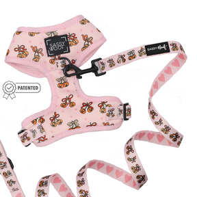 The Dog Two Piece Bundle - Sassy Lil Pumpkins from Sassy Woof features a pink harness and leash set adorned with bee and heart patterns, showcasing a patented icon, adjustable dog harness design, and Sassy Woof branding, displayed on a white background.