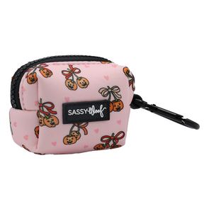 Introducing the Dog Waste Bag Holder - Sassy Lil Pumpkins by Sassy Woof: a small pink pouch adorned with a charming cherry pattern, scattered pink hearts, a black zipper, and a convenient black clip. Featuring the signature Sassy Woof label on the front, this stylish accessory is perfect as a dog waste bag holder and pairs beautifully with other items from the Sassy Lil Pumpkins Dog Collection to complement any look.