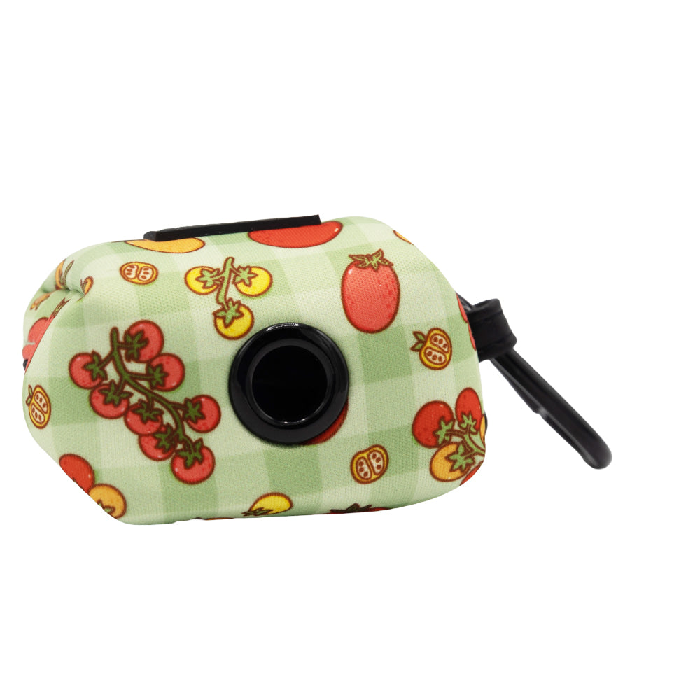 The Sassy Woof Dog Four Piece Bundle - Feeling Vine is a small, rectangular fabric pouch with a green checkered pattern and tomato illustrations, featuring a circular black dispenser opening and a black clip on one side.