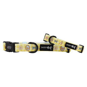 Two yellow Sassy Woof Patch Perfect dog collars with cartoon donuts, bows, and white flowers. Made from soft neoprene with black plastic buckles and sliders—adjustable for puppy growth.