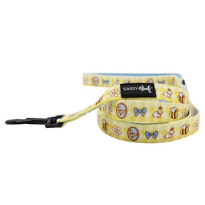 The Sassy Woof Dog Three Piece Bundle - Patch Perfect includes a yellow leash with bees, blue bows, flowers, and animal faces. It features a black metal clip and Sassy Woof label—pair it with the Patch Perfect collar for the perfect look.