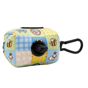 The Sassy Woof Dog Waste Bag Holder - Patch Perfect features a colorful quilted pattern with cartoon bees and bunnies, plus a black clip and an opening for dispensing black bags.
