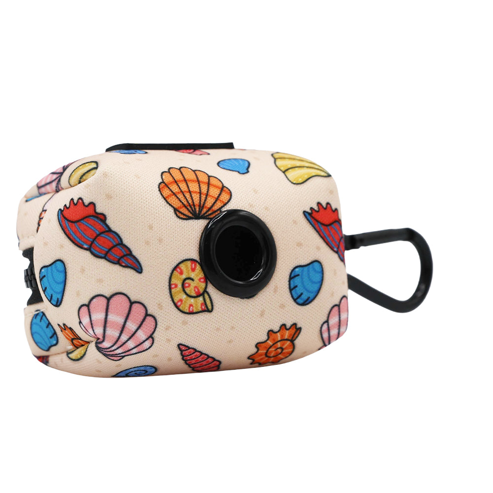 The Sassy Woof Dog Four Piece Bundle - Shell Yeah includes a beige, rectangular pouch with a black clip and colorful seashell design, featuring a black circular opening for easy waste bag dispensing—perfect with beachy dog accessories.