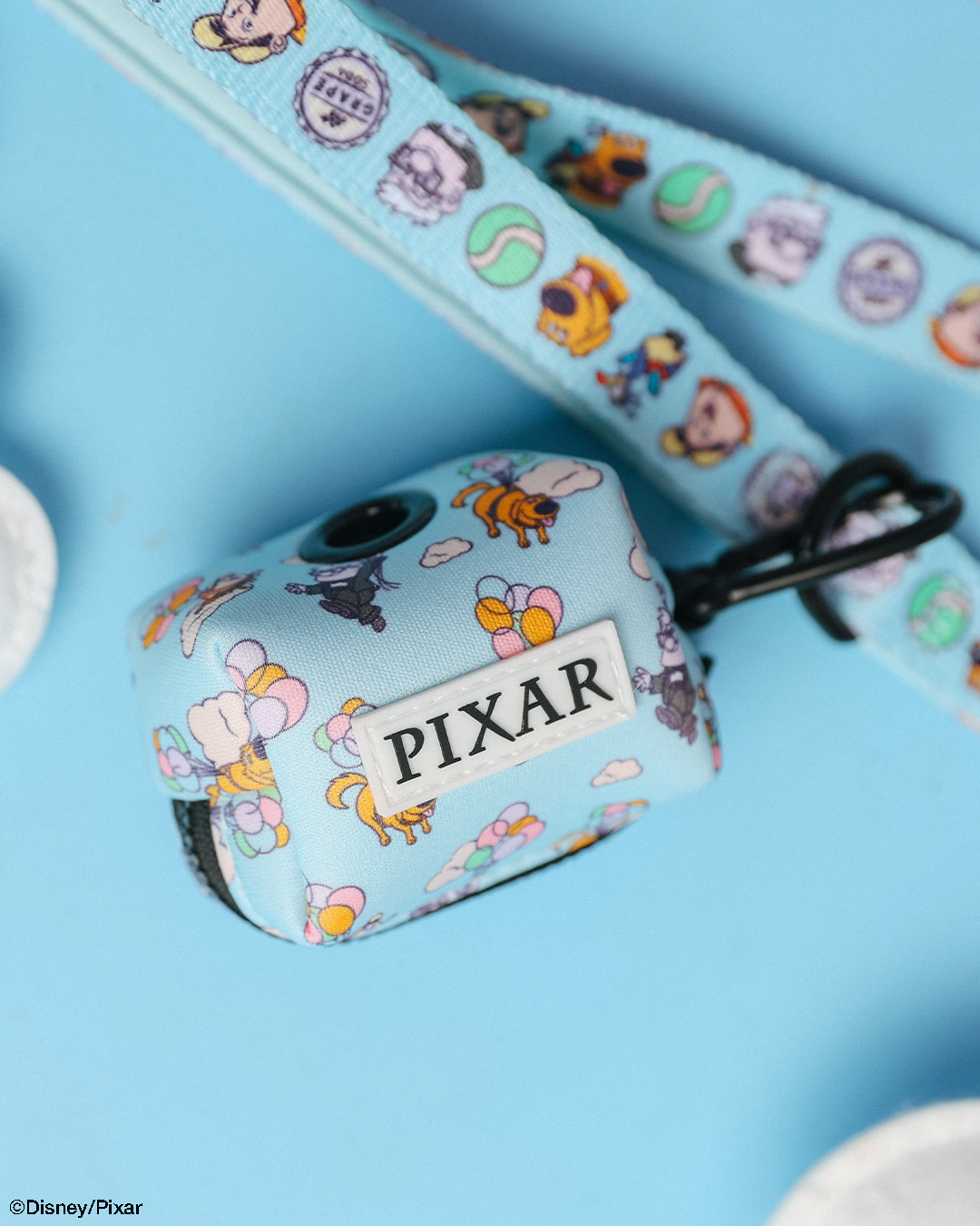 The Sassy Woof Dog Waste Bag Holder - Disney and Pixar's Up features light blue tones with cartoon characters and clouds, plus a matching lanyard. Perfect for pairing with any Disney Up dog accessories or Sassy Woof neoprene dog harness.