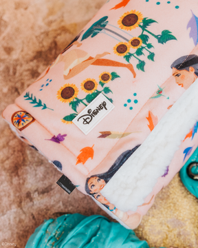 The Sassy Woof Pet Blanket - Disney's Pocahontas is a soft, pink blanket with vibrant Pocahontas, sunflowers, and leaves prints, a cozy white sherpa interior, and a visible Disney logo tag.