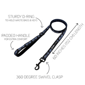 Certainly! Here’s a revised version of the sentence incorporating your product data: Black dog leash with a blue pattern from the Sassy Woof Dog Collar Three Piece Bundle – Batman™, featuring a sturdy D-ring for bags and keys, a padded handle, 60-inch (152 cm) length, and a 360-degree swivel clasp. Arrows highlight each feature on a white background.