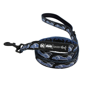 A black Batman-themed dog leash featuring blue Batmobiles and bat symbols, designed to pair perfectly with the Sassy Woof Dog Collar Three Piece Bundle - Batman™. The leash includes a metal clip and is finished with a label displaying the DC x Sassy Woof, Batman™, and Sassy Woof logos.