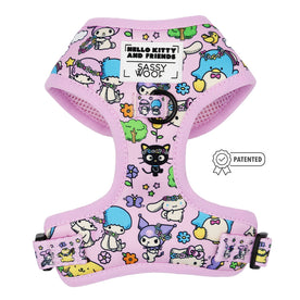 The Sassy Woof Dog Adjustable Harness – Hello Kitty® & Friends Flower Festival features a pastel pink design with colorful characters, black buckle, adjustable straps, brand labels, and a patented badge beside this stylish dog harness.