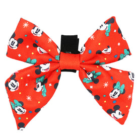 The Sassy Woof Dog Sailor Bow from the Disney Holiday Collection features a red base with Minnie Mouse faces in green bows plus colorful stars and dots. It has a black band, Velcro straps for easy attachment, and can be spot cleaned.