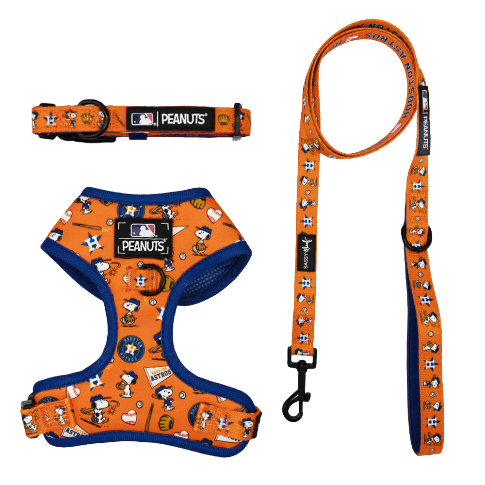 The Sassy Woof Harness Three Piece Bundle - MLB x Peanuts™ Houston Astros™ features an orange Snoopy dog harness, collar, and leash set with Peanuts characters, team logos, blue harness trim, and black clasps.