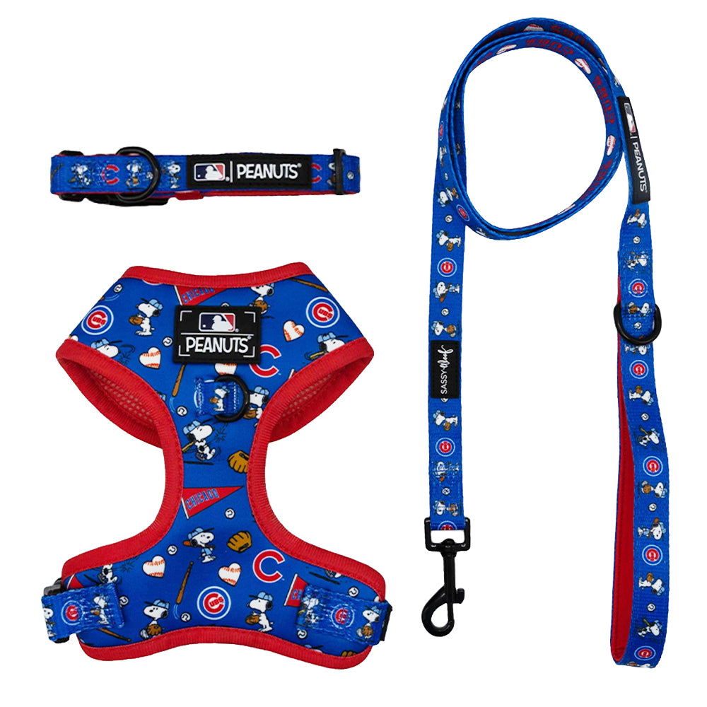 The Sassy Woof Harness Three Piece Bundle—MLB x Peanuts™ Chicago Cubs™—features a blue collar, adjustable harness, and leash with red trim and playful prints, perfect for Cubs fans who want style and team spirit for their pup.