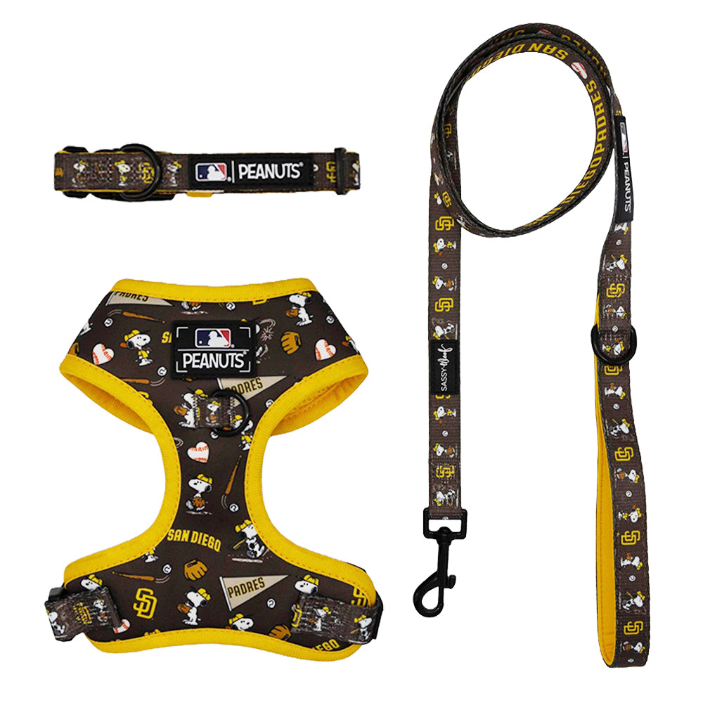 The Harness Three Piece Bundle - MLB x Peanuts™ San Diego Padres™ by Sassy Woof includes a brown and yellow harness, collar, and leash with Snoopy, Woodstock, and team logos—perfect for pups on the Puppy Growth Pawtection Plan.